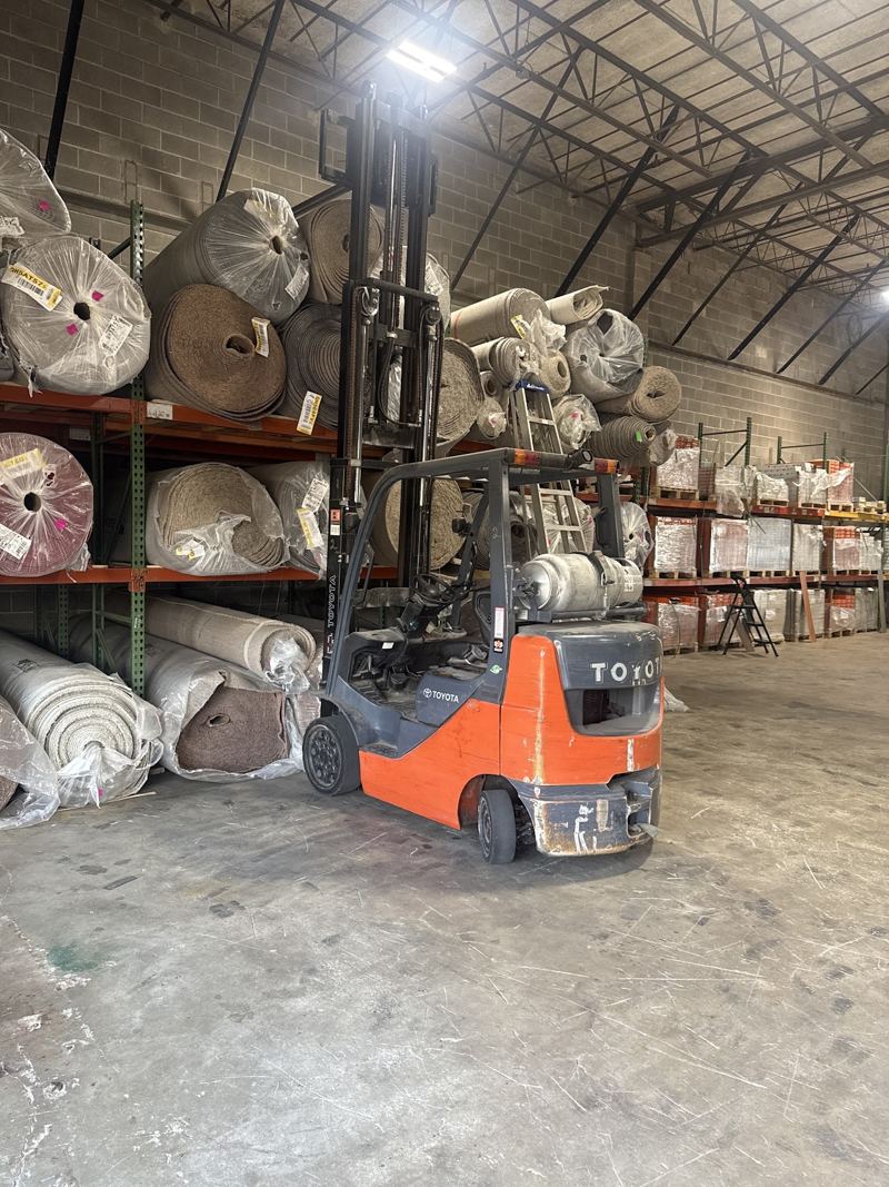 Carpet rolls on tall racks with a forklift